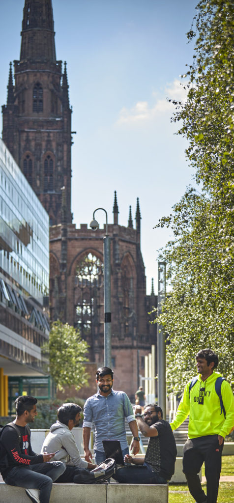 Coventry city centre with people in foreground, church steeple in background